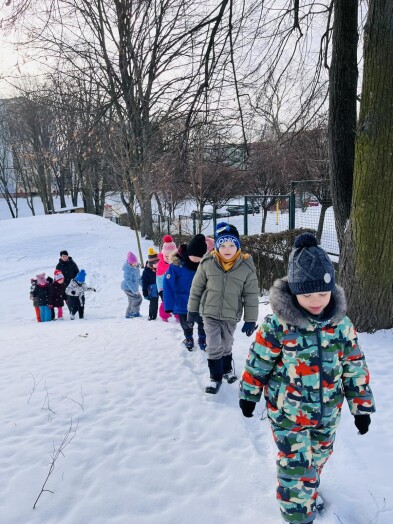 Dzieci na zimowym spacerze w ogrodzie przedszkolnym