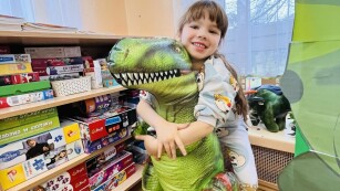 Zdjęcie dziewczynki z dmuchanym dinozaurem