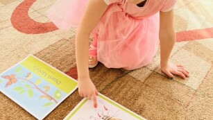 Dziewczynka rozwiązuje zadnia na dywanie z okazji Dnia Motyla