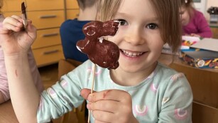 Dziewczynka maluje farbami króliczka wielkanocnego ze styropianu