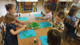 Praca plastyczna przy stolikach pt. „Nasza planeta - Ziemia” techniką wydzieranki. Dzieci wydzierają małe kawałki  kolorowego papieru i wyklejają wzór planety na kartce.