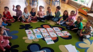 Zajęcia dydaktyczne na dywanie. Dzieci siedzą w kole na dywanie i zapoznają się z kodeksem małego ekologa. Każde dziecko wybiera jeden obrazek i opisuje co jest na obrazku.